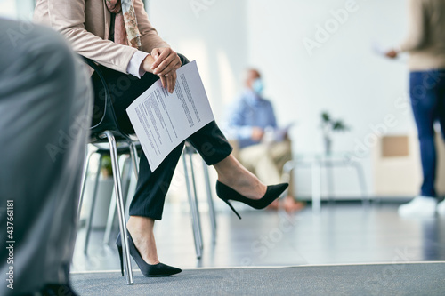 Unrecognizable businesswoman sitting at office building hallway and waiting for job interview.