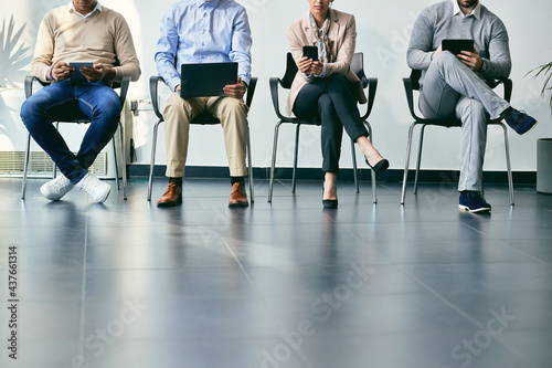 Unrecognizable business people using wireless technology while anticipating job interview. © Drazen