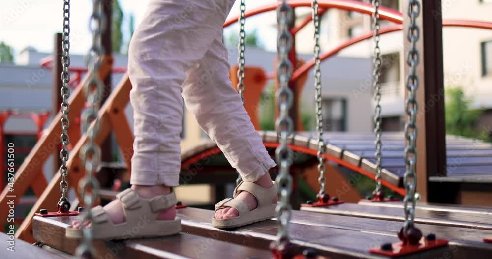 kid is crossing the wooden chain bridge, swinging bridge, having fun at the outdoor playground kid is crossing the wooden chain bridge, swinging bridge, having fun at the outdoor playground