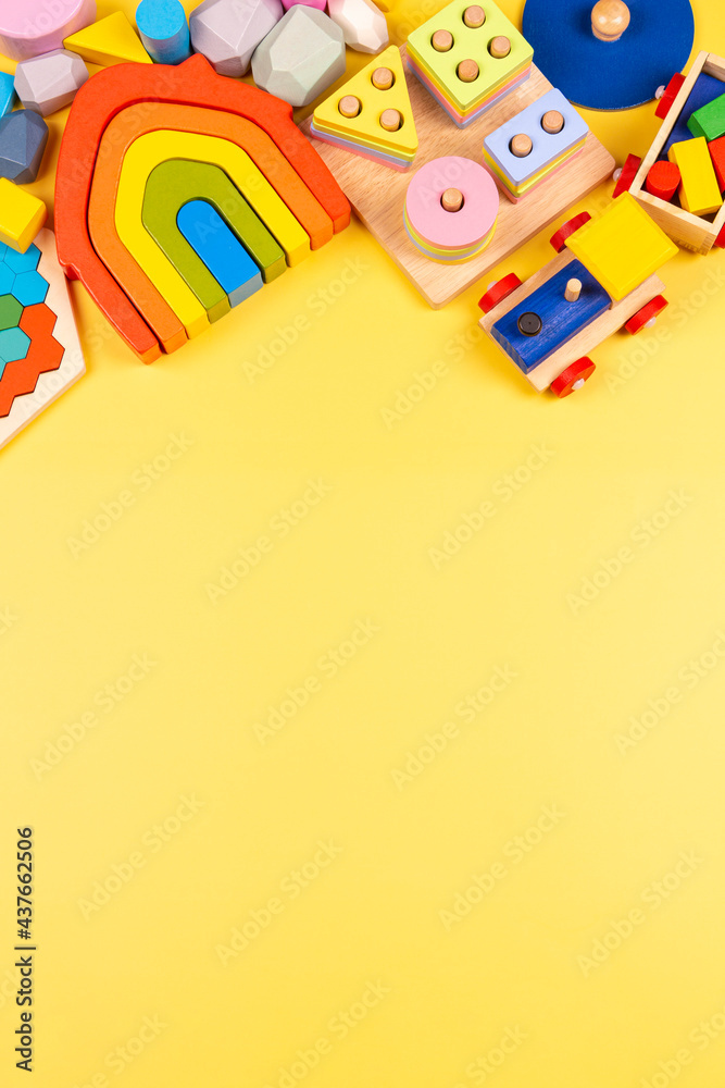 Fototapeta Baby kids toys frame. Educational wooden plastic and fluffy toys for children on yellow background. Top view, flat lay