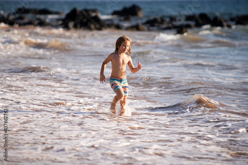 little child running on the tropical beach. Boy playing sea waves on vacation sea in the summer holiday. Kid in nature at seashore. Children walking at seaside.