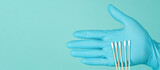 Cotton sticks for swab in hand with blue medical gloves or latex glove on mint green or Tiffany Blue background.covid-19 concept