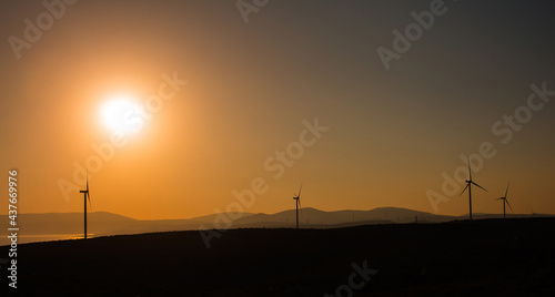 View of wind turbine, Aegean sea and landscpae at sunset captured in Sigacik / Seferihisar district of Izmir / Turkey. Wind power turbines for clean, renewable energy. Sustainability concept.