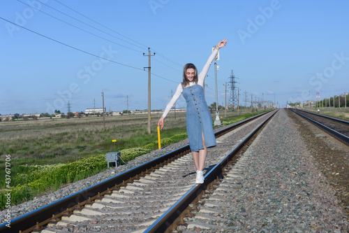 Young woman walks on the rails on railroad