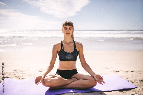 Fit woman meditating on beach © Jacob Lund