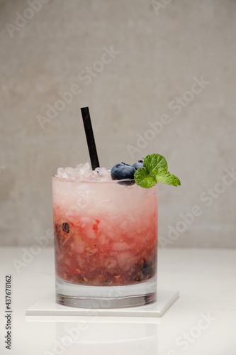 Blueberry mojito cocktail with blueberries, lime, mint and ice in glass on gray background. Summer cold alcoholic non-alcoholic drinks, beverages and cocktails. Front view with copy space.