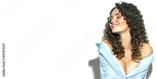 Beautiful young woman with curly hair posing and smiling, beauty model portrait, closeup. Beautiful happy sexy model girl in white cotton shirt. Flying hair, perfect make-up and Hairstyle.