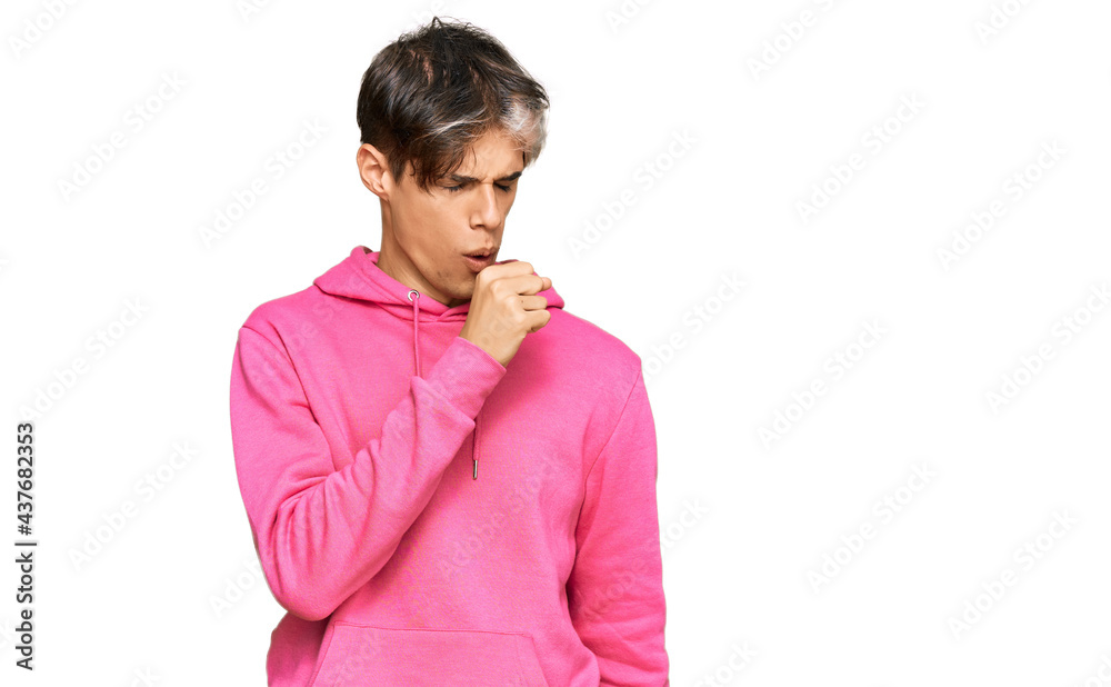 Young hispanic man wearing casual pink sweatshirt feeling unwell and coughing as symptom for cold or bronchitis. health care concept. Young hispanic man wearing casual pink sweatshirt feeling unwell and coughing as symptom for cold or bronchitis. health care concept.
