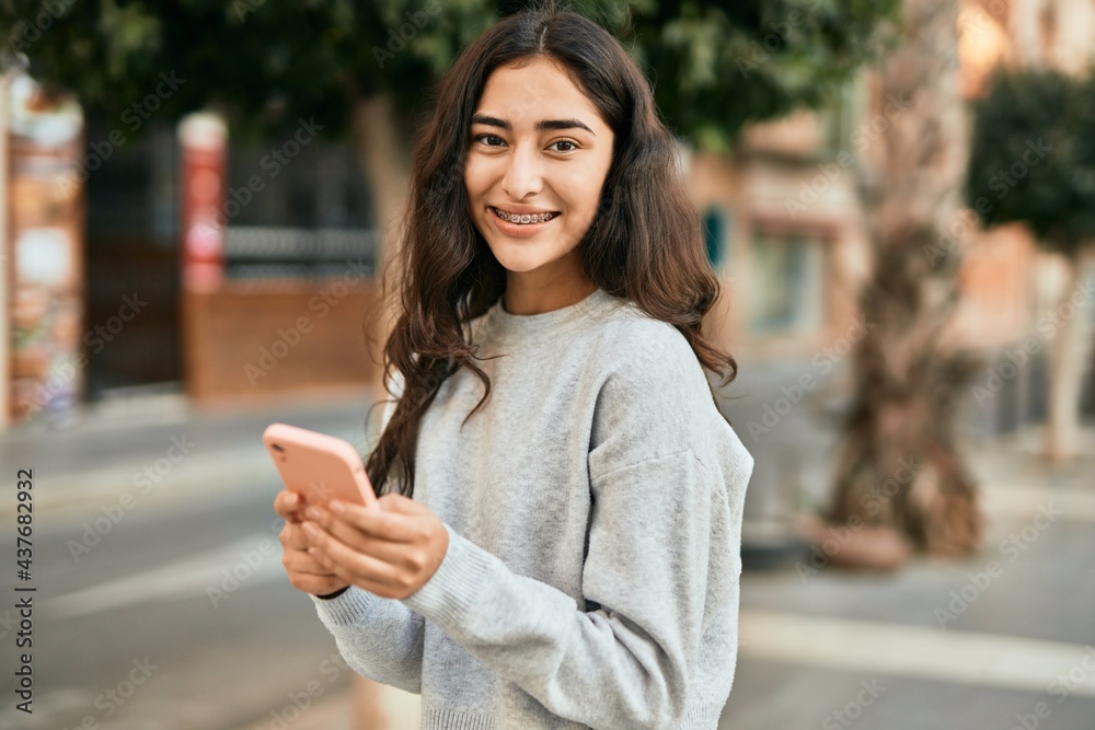 Young middle east girl smiling happy using smartphone at the city. Young middle east girl smiling happy using smartphone at the city.