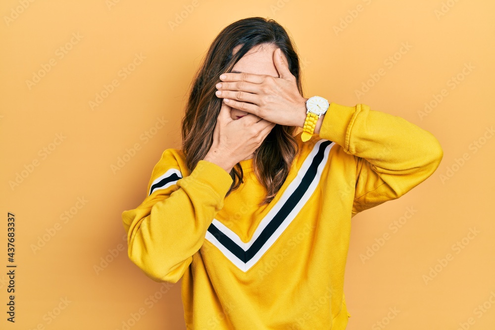 Young hispanic girl wearing casual clothes covering eyes and mouth with hands, surprised and shocked. hiding emotion Young hispanic girl wearing casual clothes covering eyes and mouth with hands, surprised and shocked. hiding emotion