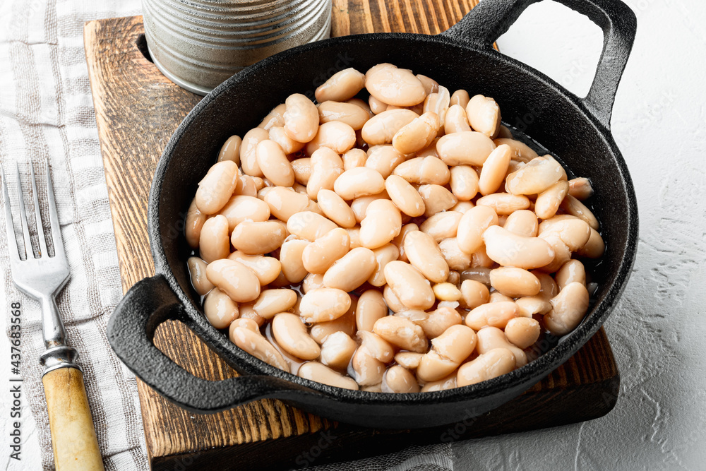 Canned white beans, in cast iron frying pan, on white stone  surface