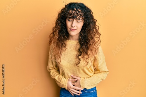 Young hispanic girl wearing casual clothes with hand on stomach because indigestion, painful illness feeling unwell. ache concept.