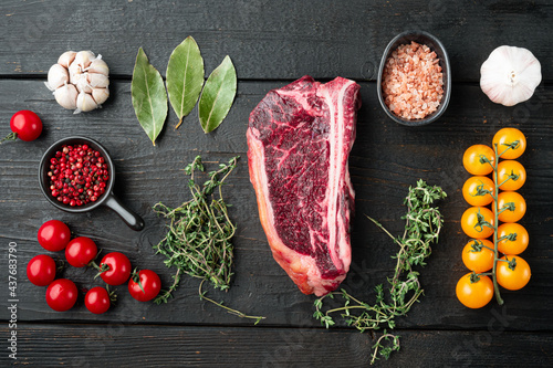 Raw fresh marbled meat black angus club steak and ingredients on black wooden table background, top view flat lay