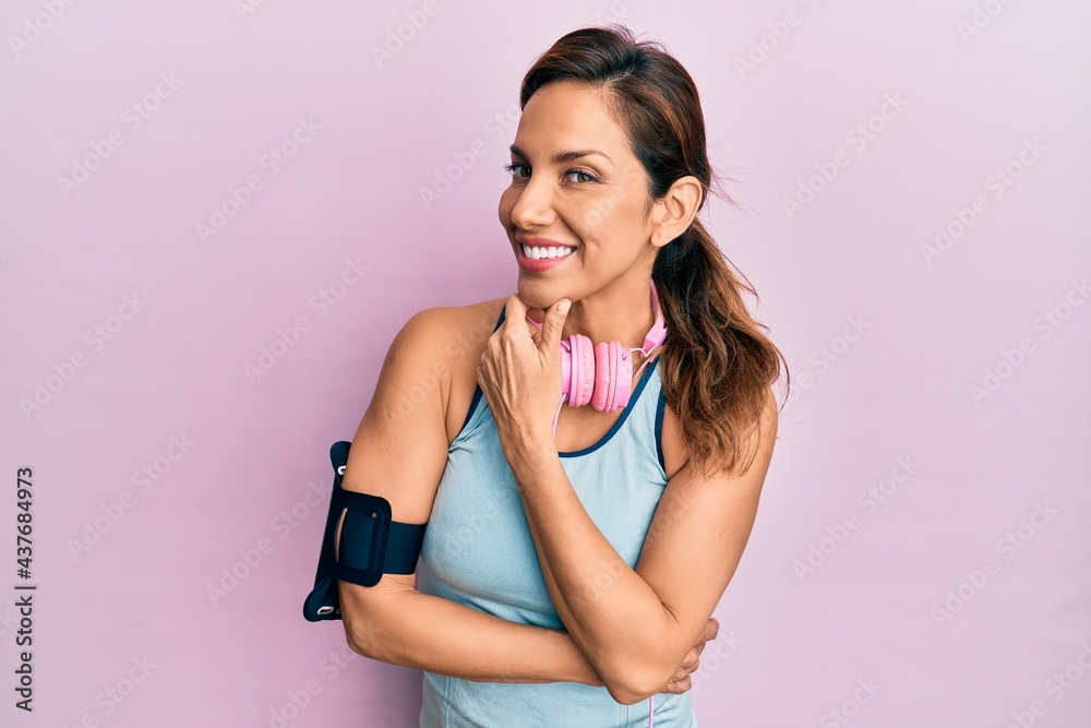 Young latin woman wearing gym clothes and using headphones smiling looking confident at the camera with crossed arms and hand on chin. thinking positive. Young latin woman wearing gym clothes and using headphones smiling looking confident at the camera with crossed arms and hand on chin. thinking positive.