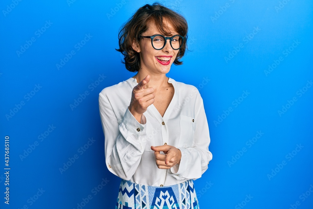 Young brunette woman wearing casual clothes and glasses pointing fingers to camera with happy and funny face. good energy and vibes. Young brunette woman wearing casual clothes and glasses pointing fingers to camera with happy and funny face. good energy and vibes.