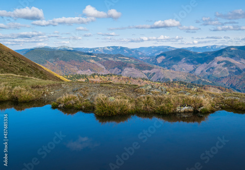 Small picturesque lake with clouds reflections at the Strymba Mount. Beautiful autumn day in Carpathian Mountains near Kolochava village, Transcarpathia, Ukraine.