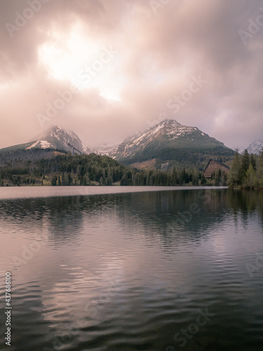 Mountain lake with snowy mountains in the background and cloudy sky.