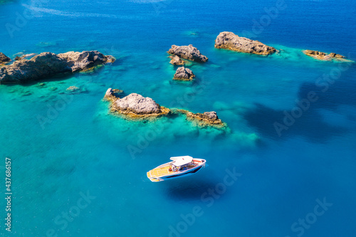 Speed boat on blue sea at sunrise in summer. Aerial view of motorboat on sea bay, rocks in clear azure water. Tropical landscape with yacht, stones. Top view from drone. Travel in Oludeniz, Turkey © den-belitsky