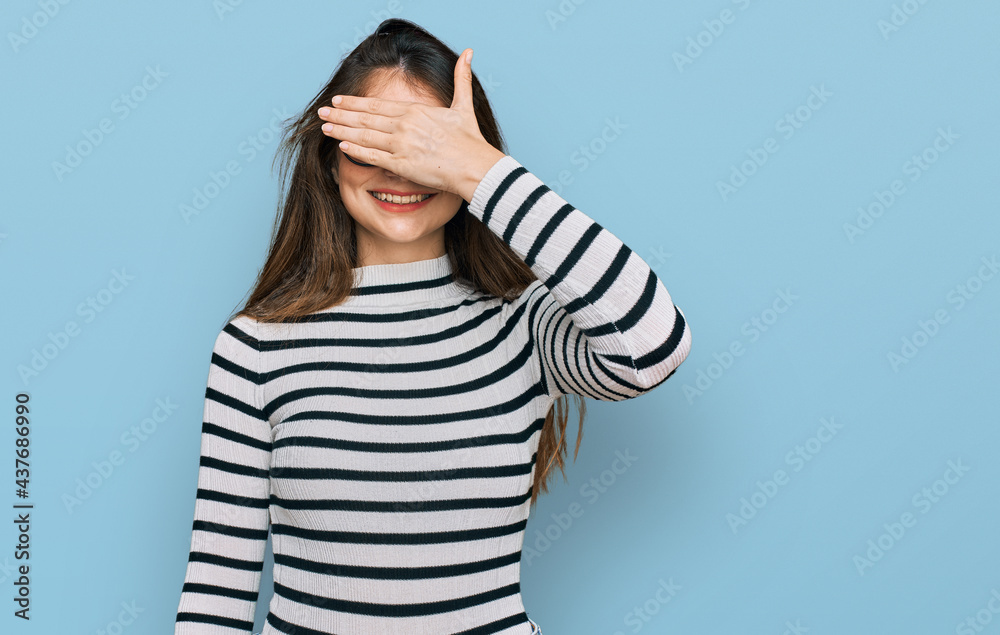 Young beautiful teen girl wearing casual clothes and glasses smiling and laughing with hand on face covering eyes for surprise. blind concept. Young beautiful teen girl wearing casual clothes and glasses smiling and laughing with hand on face covering eyes for surprise. blind concept.