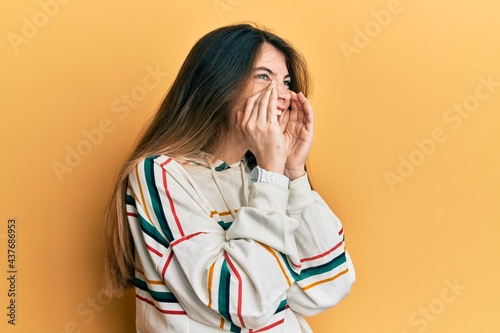 Young caucasian woman wearing casual clothes shouting angry out loud with hands over mouth
