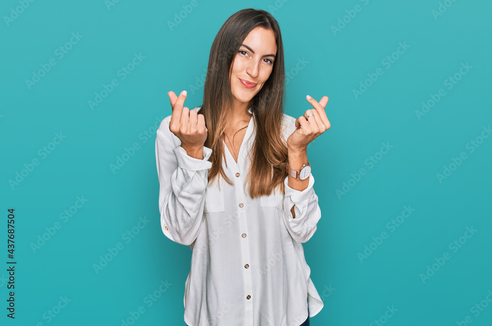 Young beautiful woman wearing casual clothes doing money gesture with hands, asking for salary payment, millionaire business Young beautiful woman wearing casual clothes doing money gesture with hands, asking for salary payment, millionaire business