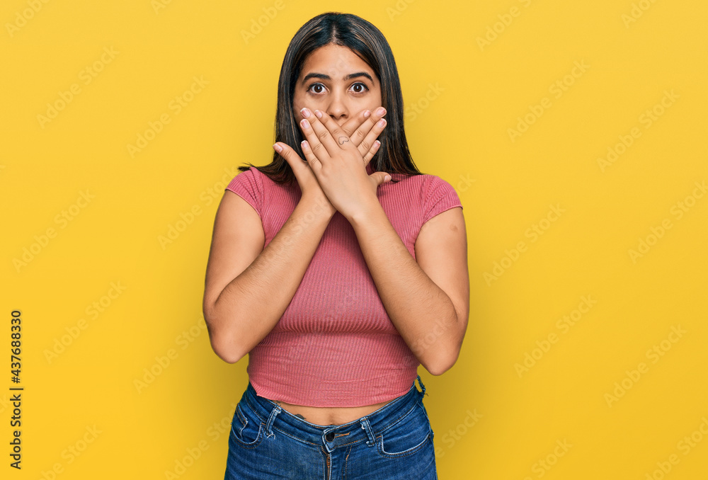 Young hispanic girl wearing casual t shirt shocked covering mouth with hands for mistake. secret concept. Young hispanic girl wearing casual t shirt shocked covering mouth with hands for mistake. secret concept.