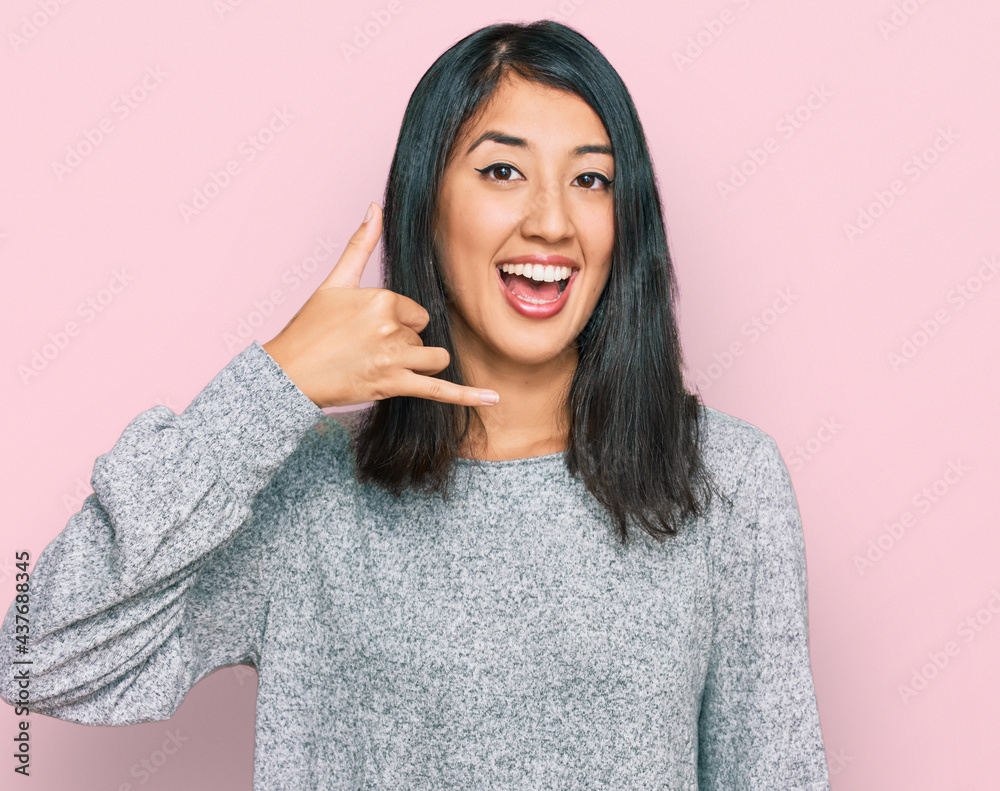 Beautiful asian young woman wearing casual clothes smiling doing phone gesture with hand and fingers like talking on the telephone. communicating concepts. Beautiful asian young woman wearing casual clothes smiling doing phone gesture with hand and fingers like talking on the telephone. communicating concepts.