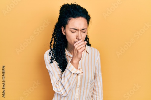 Young hispanic woman with curly hair wearing casual striped shirt feeling unwell and coughing as symptom for cold or bronchitis. health care concept.