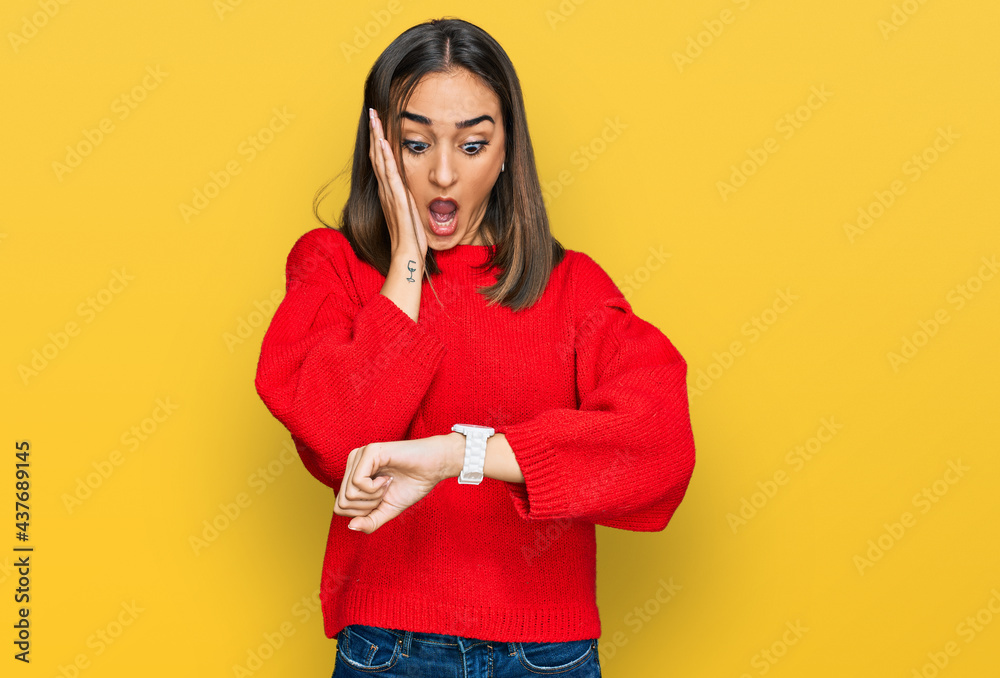 Beautiful brunette woman wearing casual winter sweater looking at the watch time worried, afraid of getting late Beautiful brunette woman wearing casual winter sweater looking at the watch time worried, afraid of getting late