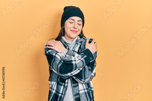 Photos Beautiful woman with blue eyes wearing wool cap hugging oneself happy and positive, smiling confident
