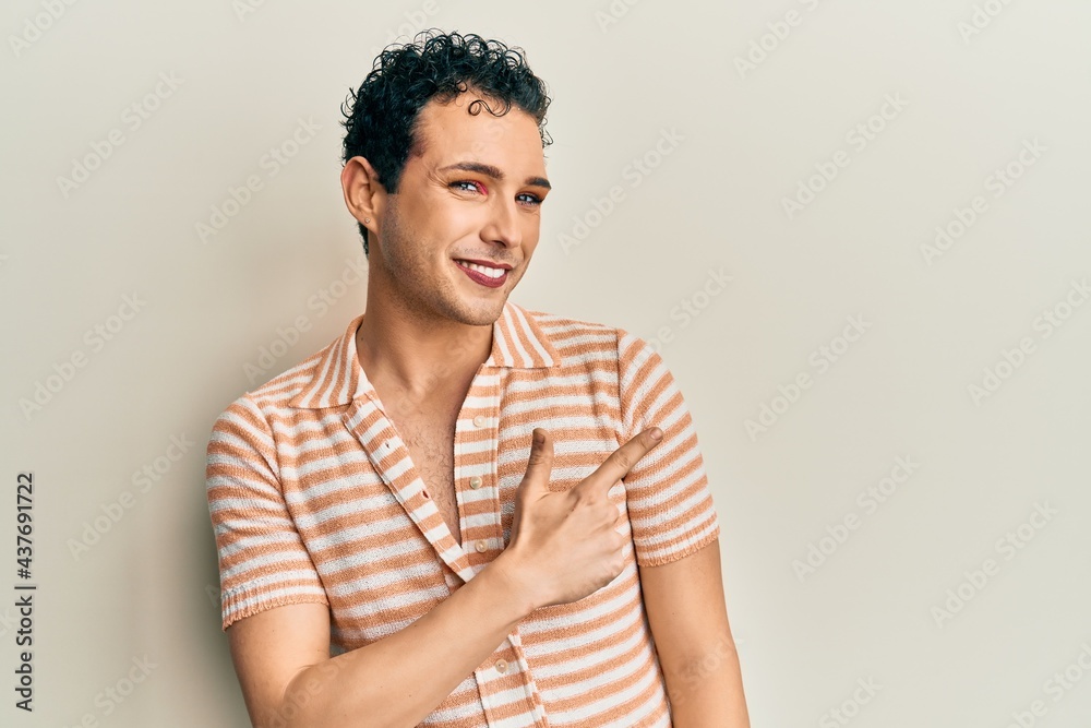 Handsome man wearing make up wearing casual t shirt cheerful with a smile of face pointing with hand and finger up to the side with happy and natural expression on face Handsome man wearing make up wearing casual t shirt cheerful with a smile of face pointing with hand and finger up to the side with happy and natural expression on face