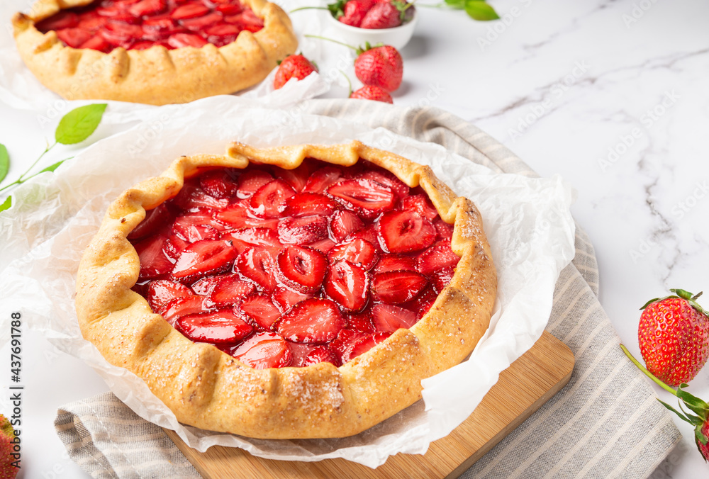 Homemade galettes with strawberries on white marble background Homemade galettes with strawberries on white marble background