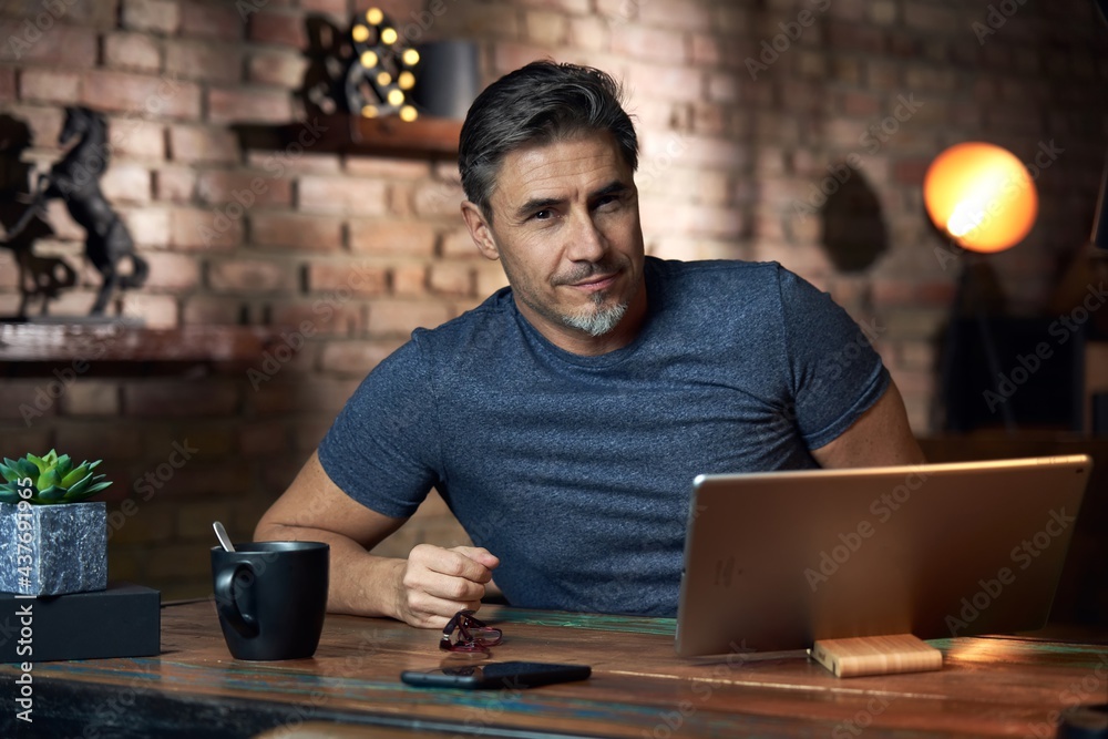 50s man working online with laptop computer at home sitting at desk, smiling. Home office, browsing internet, study room, Businessman working from home. 50s man working online with laptop computer at home sitting at desk, smiling. Home office, browsing internet, study room, Businessman working from home.