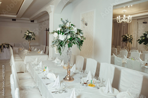 flower arrangement of roses and decorations of green twigs and transparent beads on the wedding table