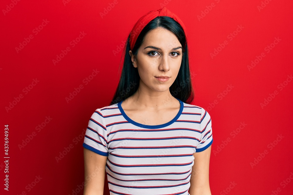Young hispanic woman wearing casual clothes with serious expression on face. simple and natural looking at the camera. Young hispanic woman wearing casual clothes with serious expression on face. simple and natural looking at the camera.
