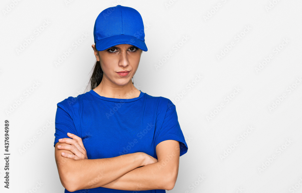 Young hispanic girl wearing delivery courier uniform skeptic and nervous, disapproving expression on face with crossed arms. negative person.