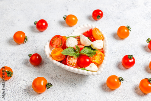Delicious Italian caprese salad with sliced red and orange cherry tomatoes and mozzarela balls.
