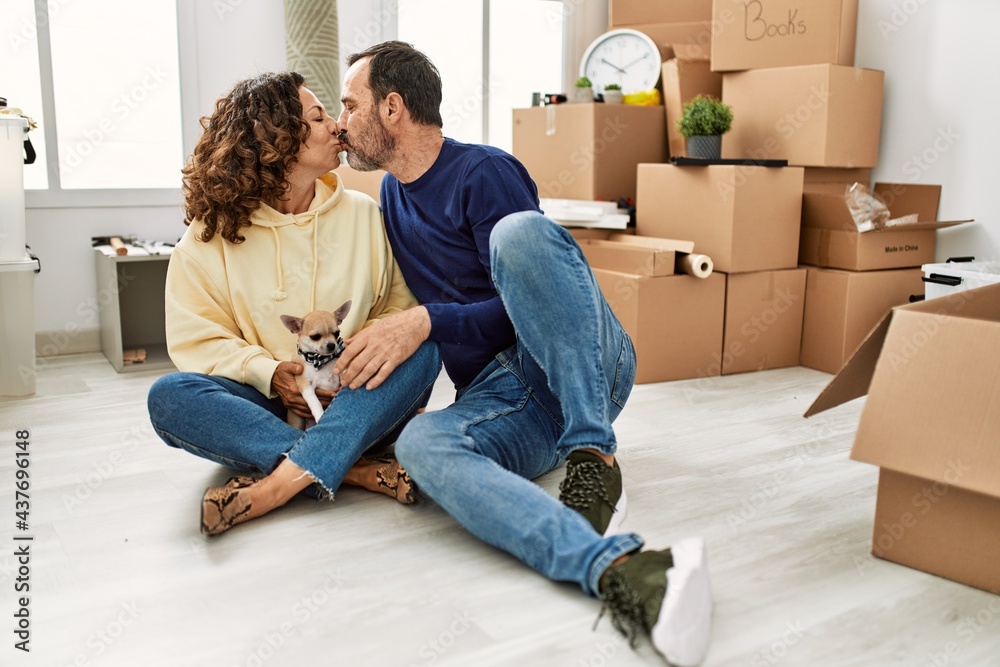 Middle age hispanic couple smiling happy sitting on the floor with dog at new home. Middle age hispanic couple smiling happy sitting on the floor with dog at new home.