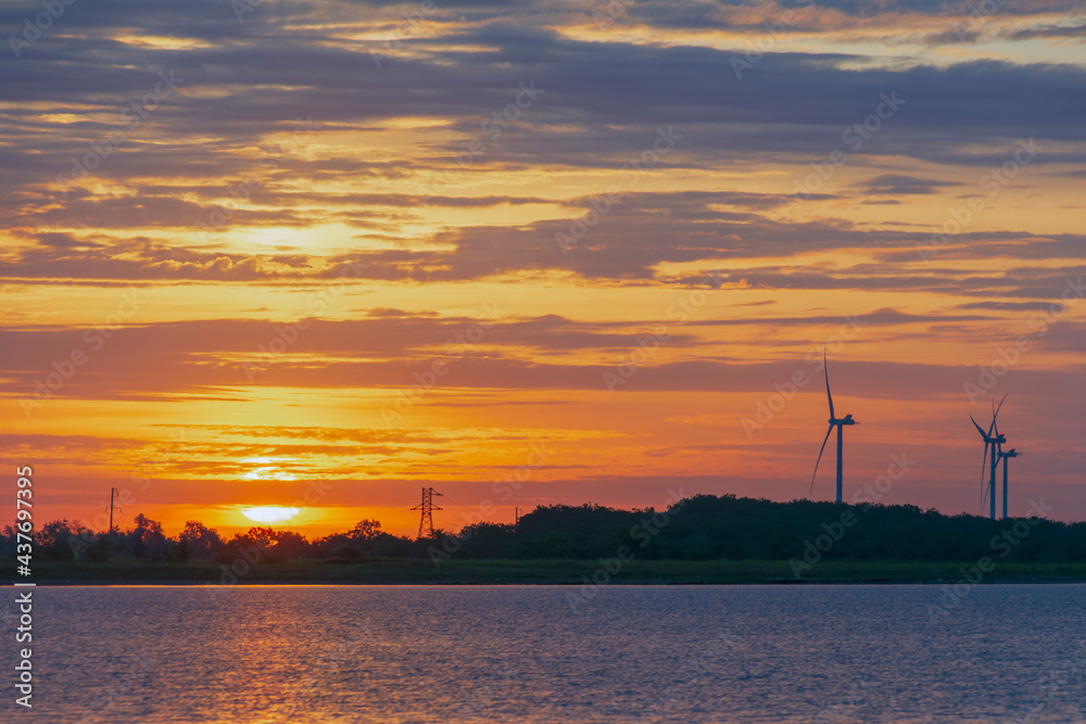 silhouette of wind turbine generating electricity on sunset