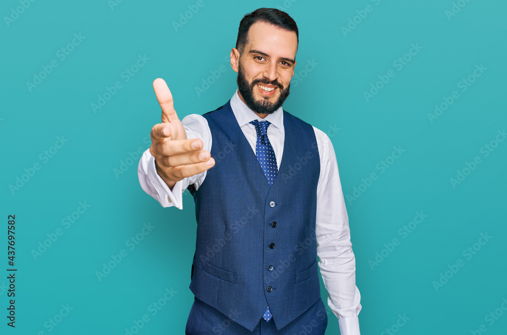 Young man with beard wearing business vest smiling friendly offering handshake as greeting and welcoming. successful business. Young man with beard wearing business vest smiling friendly offering handshake as greeting and welcoming. successful business.