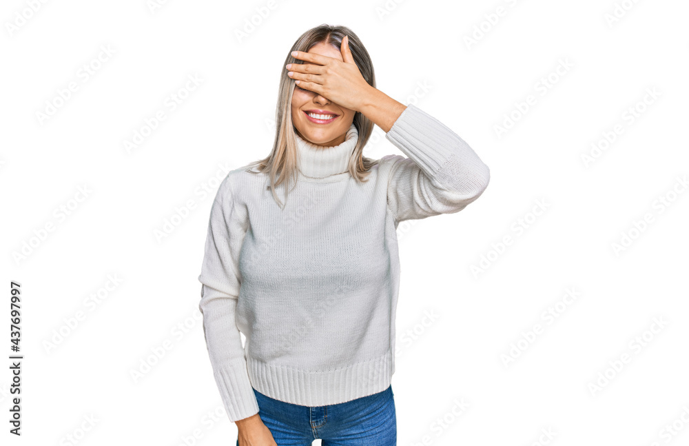 Beautiful blonde woman wearing casual turtleneck sweater smiling and laughing with hand on face covering eyes for surprise. blind concept. Beautiful blonde woman wearing casual turtleneck sweater smiling and laughing with hand on face covering eyes for surprise. blind concept.