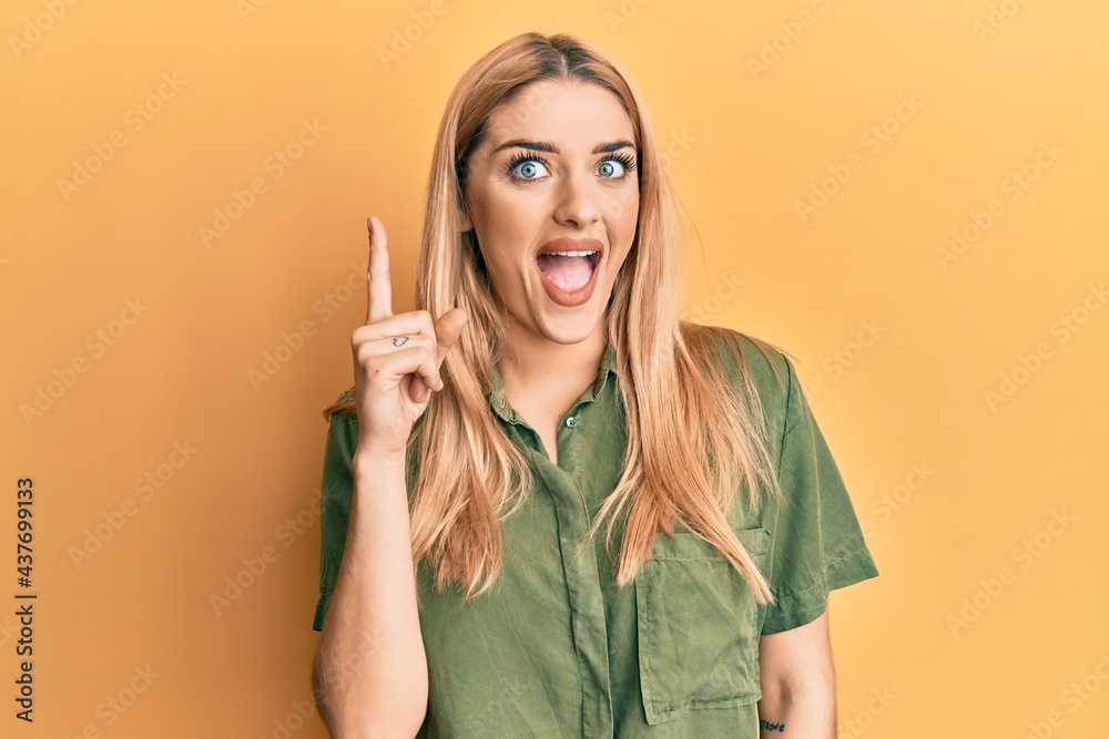 Young caucasian woman wearing casual clothes pointing finger up with successful idea. exited and happy. number one. Young caucasian woman wearing casual clothes pointing finger up with successful idea. exited and happy. number one.