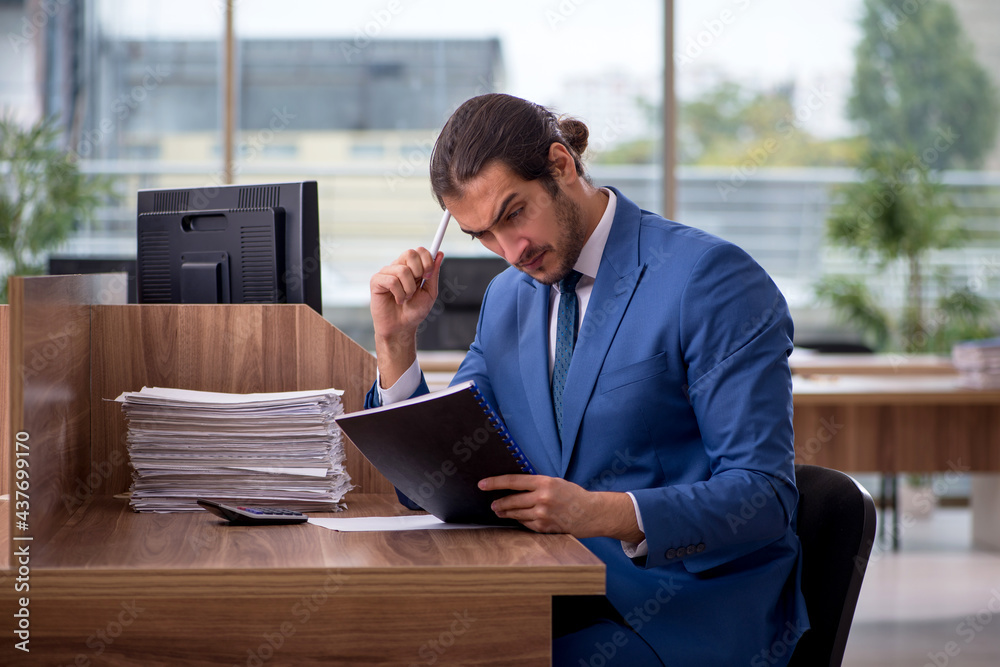 Young male employee unhappy with excessive work in the office Young male employee unhappy with excessive work in the office