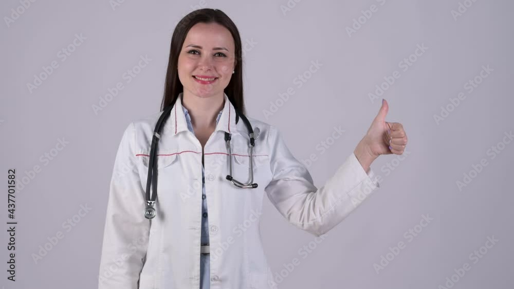Friendly female doctor in medical Uniform standing in hospital corridor showing thumbs up isolated on white background. Health care and medical concept. Medical workers. Friendly female doctor in medical Uniform standing in hospital corridor showing thumbs up isolated on white background. Health care and medical concept. Medical workers.