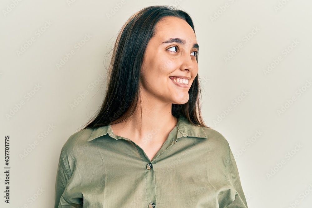 Young hispanic woman wearing casual clothes looking away to side with smile on face, natural expression. laughing confident. Young hispanic woman wearing casual clothes looking away to side with smile on face, natural expression. laughing confident.