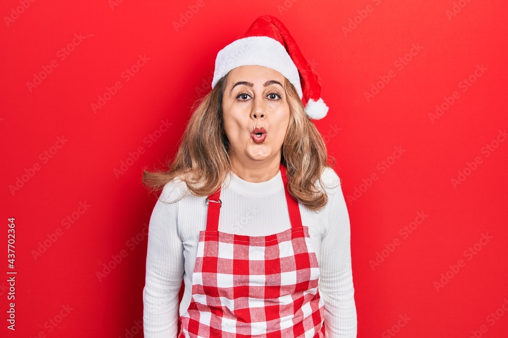 Middle age caucasian woman wearing cook apron and christmas hat scared and amazed with open mouth for surprise, disbelief face Middle age caucasian woman wearing cook apron and christmas hat scared and amazed with open mouth for surprise, disbelief face