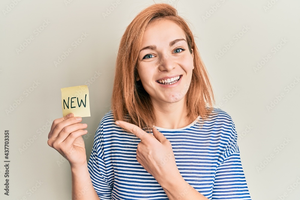 Young caucasian woman holding reminder with new word smiling happy pointing with hand and finger Young caucasian woman holding reminder with new word smiling happy pointing with hand and finger