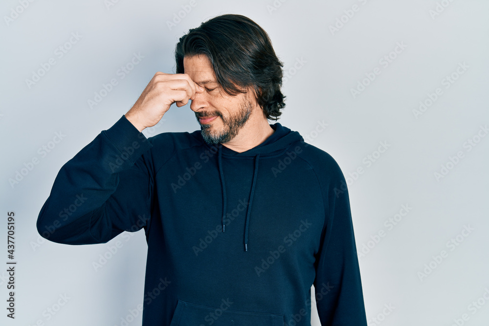Middle age caucasian man wearing casual sweatshirt tired rubbing nose and eyes feeling fatigue and headache. stress and frustration concept. Middle age caucasian man wearing casual sweatshirt tired rubbing nose and eyes feeling fatigue and headache. stress and frustration concept.