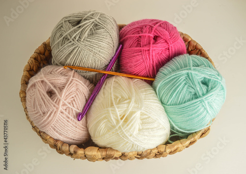 woolen balls with crochet hooks in basket