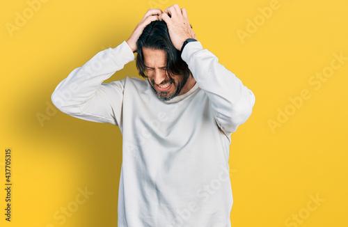 Middle age caucasian man wearing casual clothes suffering from headache desperate and stressed because pain and migraine. hands on head.